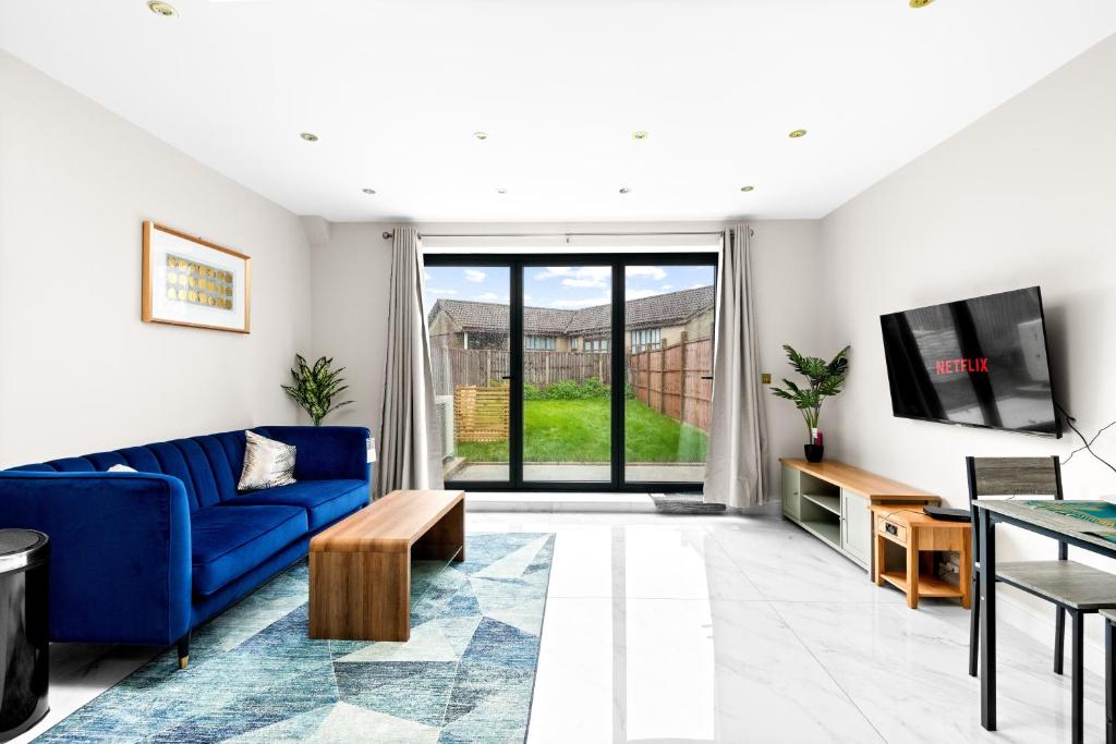 a living room with a blue couch and a tv at Stylish Sparkling Brand New 2 bed house in Heston