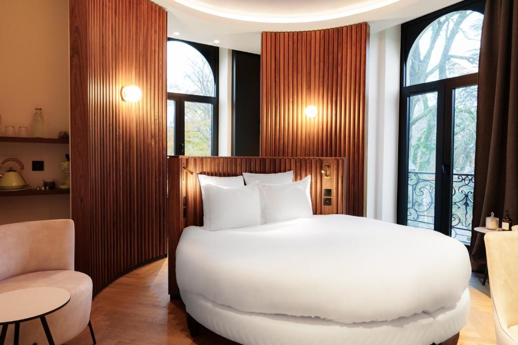 a bedroom with a large white bed and a chair at Bienheureux Hôtel & Restaurant in Wasquehal