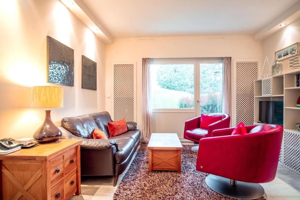 - un salon avec un canapé en cuir et un fauteuil rouge dans l'établissement Les Aiguilles du Brevent - Grand Appt Renove - Central - Terrasse avec Vue, à Chamonix-Mont-Blanc