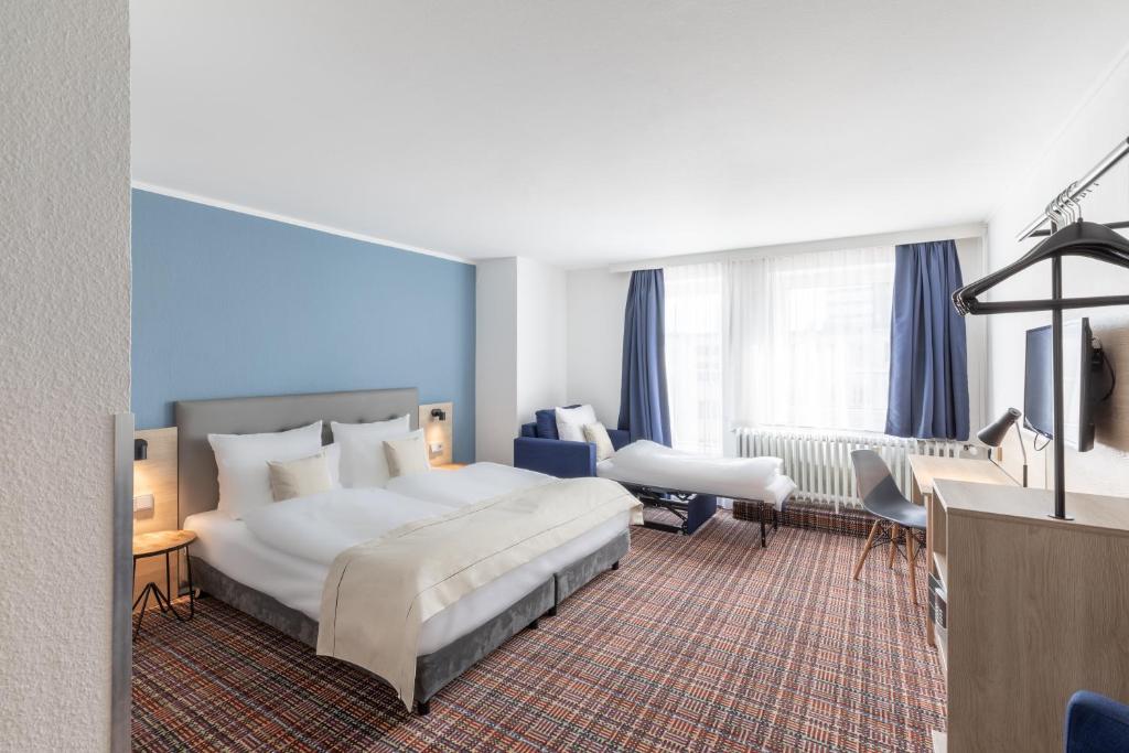 ein Hotelzimmer mit einem großen Bett und einem Schreibtisch in der Unterkunft theAmbassador Hotel I Essen City in Essen