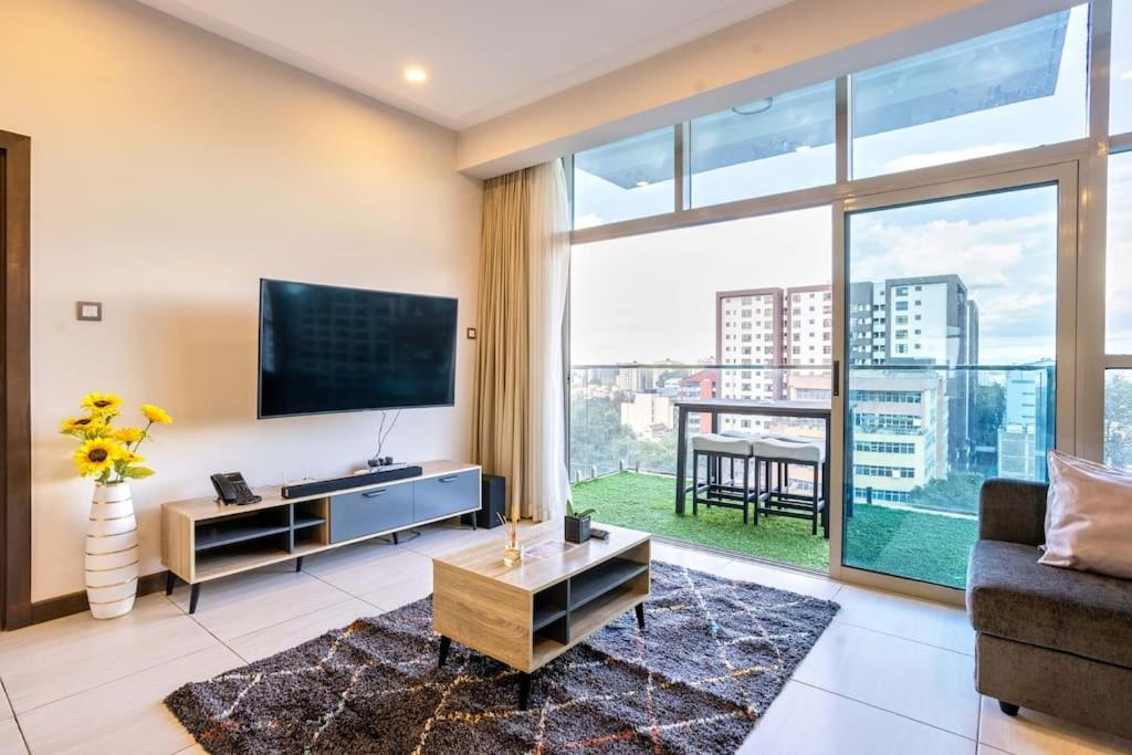 a living room with a tv and a large window at Spacious 1 bedroom Apt at Skynest (709) in Nairobi