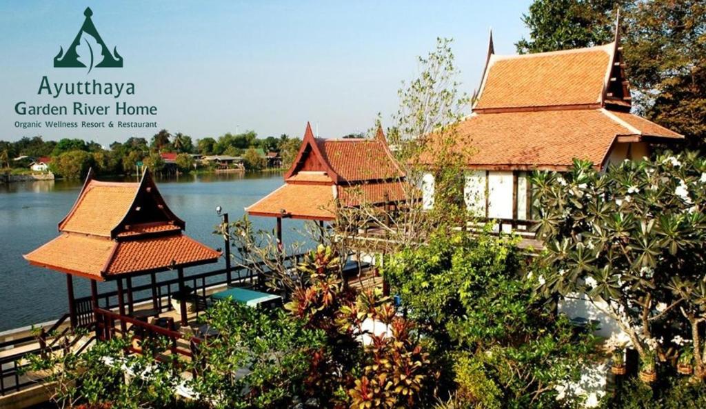 a group of pavilions on the water next to a house at Ayutthaya Garden River Home in Ban Bang Krasan