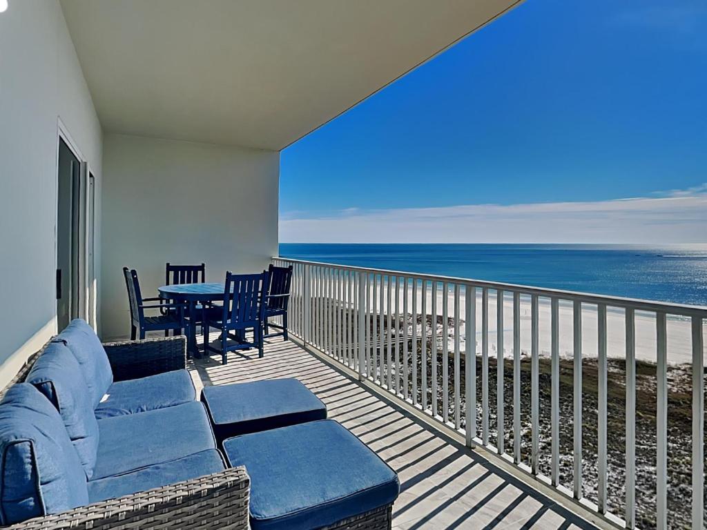 a balcony with a couch and a table and the ocean at Tidewater Orange Beach #1003 in Orange Beach