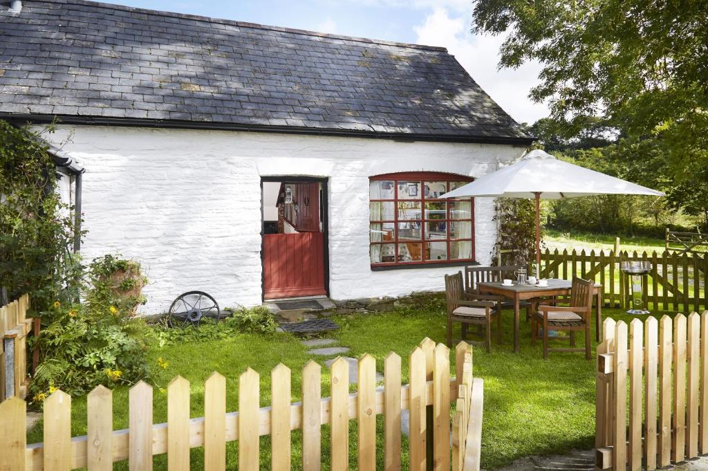 a white house with a table and an umbrella at Y Cartws near Llangrannog in Llangrannog