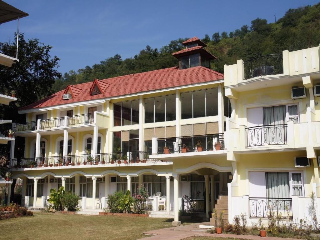 a large white building with a red roof at Riverside Resorts in Devaprayāg