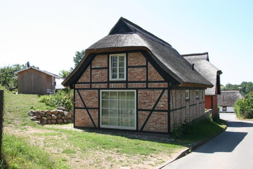 ein altes Haus mit einem Strohdach in der Unterkunft Dorphus in Neuenkirchen auf Rügen