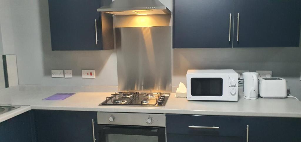 La cocina está equipada con fogones y microondas. en Coventry Rise Home en Coventry