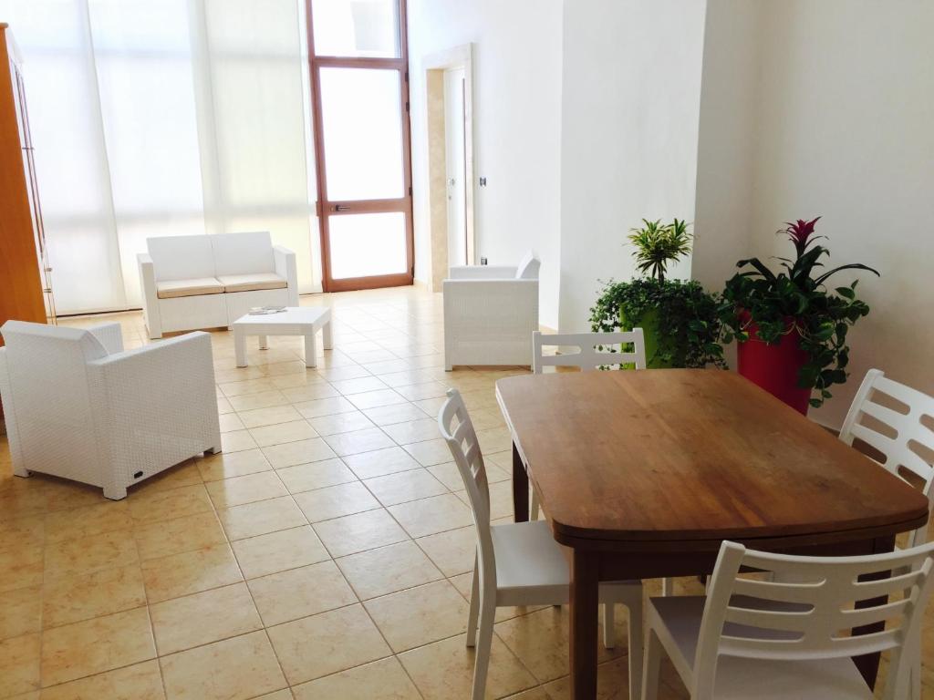 ein Esszimmer mit einem Holztisch und weißen Stühlen in der Unterkunft B&B Cadorna in Leverano