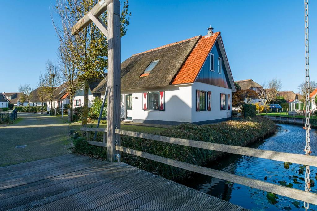 uma casa com um telhado laranja ao lado de uma cerca de madeira em Buitenplaats 27 Callantsoog em Callantsoog