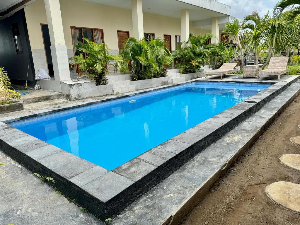 een zwembad met blauw water voor een huis bij Dega Gardens in Canggu