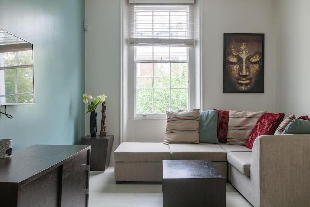 uma sala de estar com um sofá e uma janela em Charming 1 BR flat near Hyde Park em Londres