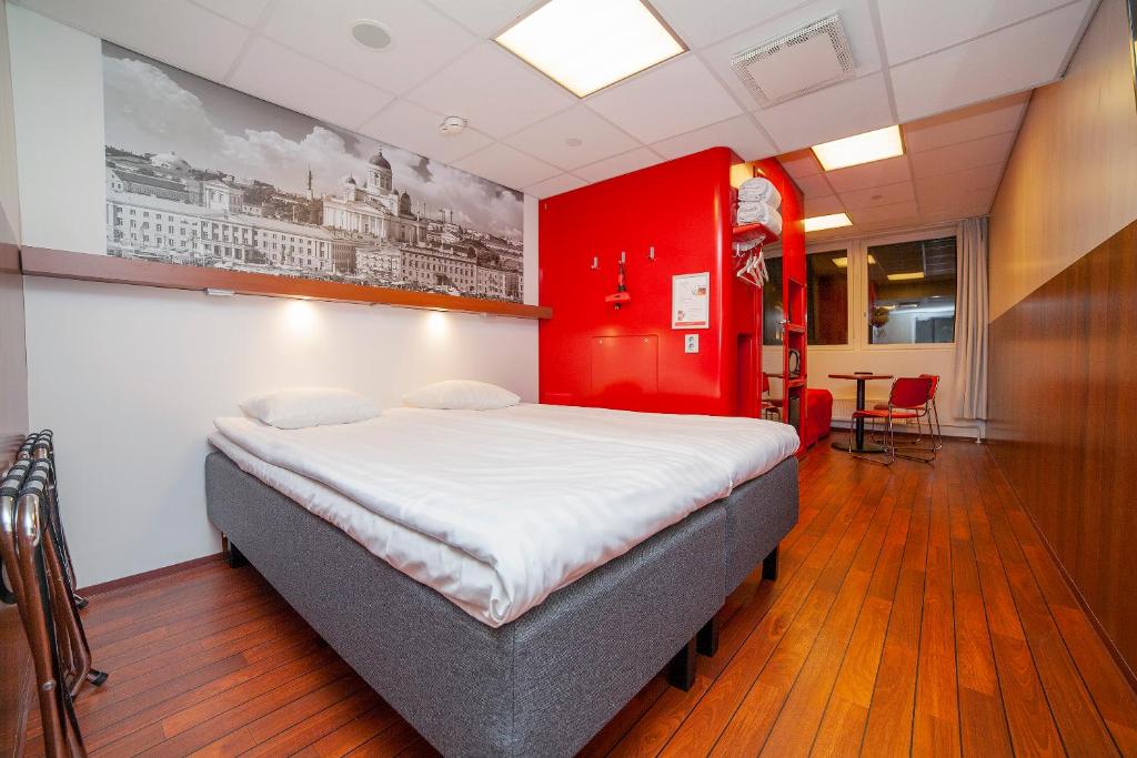 a bedroom with a large bed with a red wall at Omena Hotel Helsinki City Centre in Helsinki