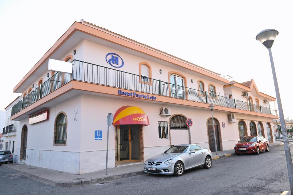 a building with a car parked in front of it at Hostal Puerto Lepe in Lepe