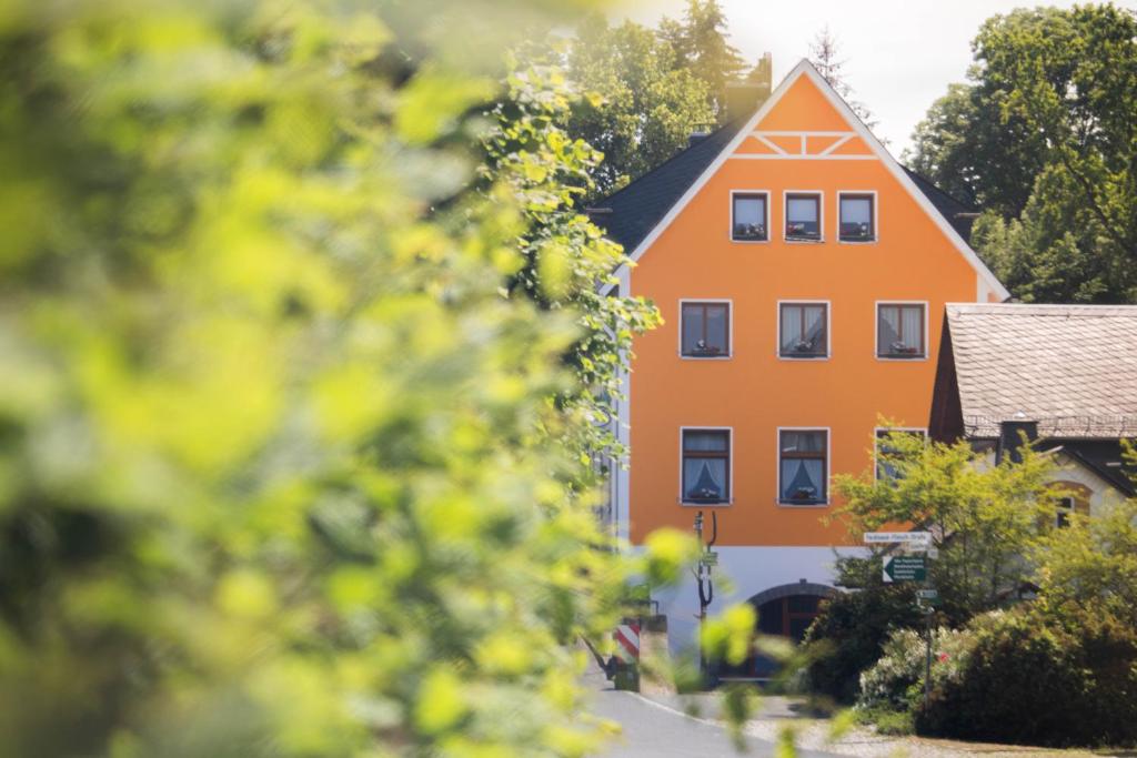 un edificio naranja es visto a través de los árboles en Gasthof Blankenberg 