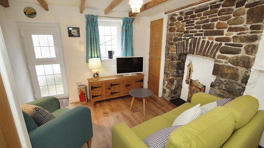 a living room with a couch and a stone fireplace at Bwthyn Bach in The Mumbles