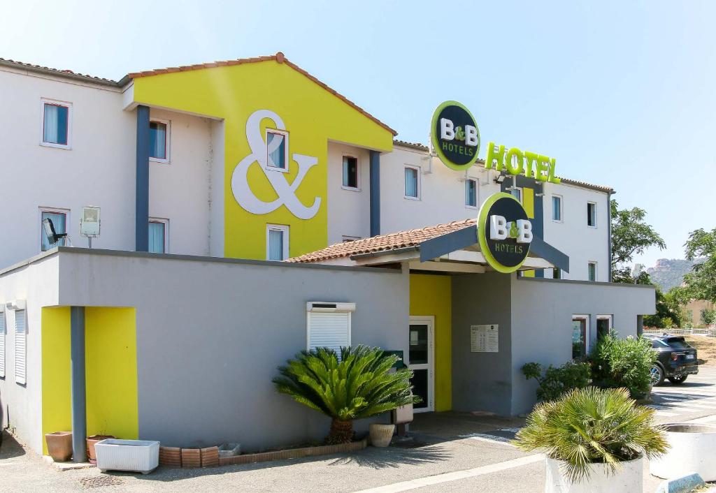 un hôtel avec un bâtiment jaune et blanc dans l'établissement B&B HOTEL Fréjus Roquebrune-sur-Argens, à Roquebrune-sur Argens