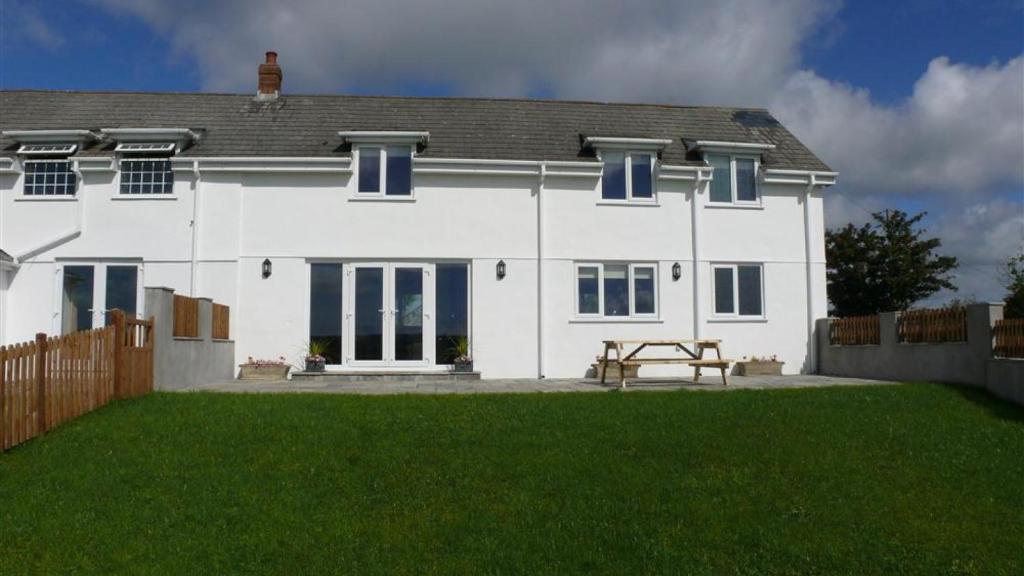 a white house with a bench in front of it at Llanelen Farm Sleeps 2 in Llanrhidian