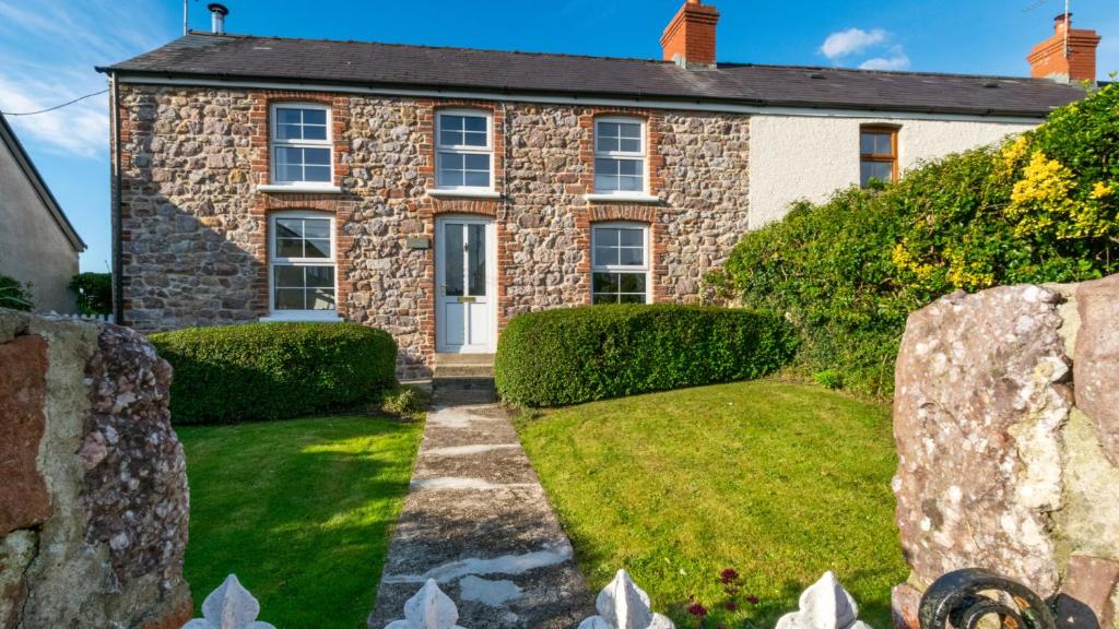 an old stone house with a garden in front of it at West End Cottage in Llangennith