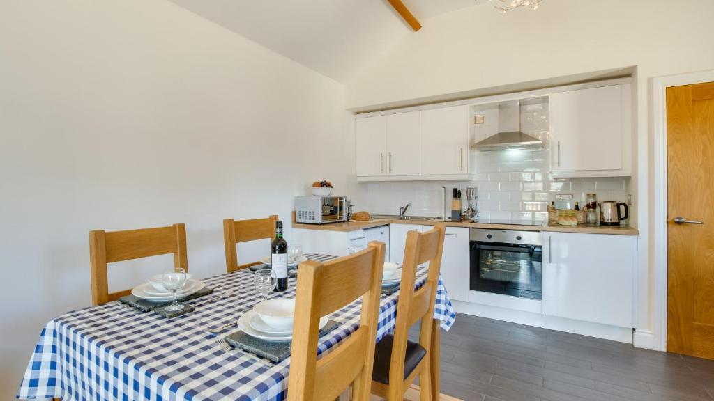 a kitchen and dining room with a table and chairs at Bluebell Cottage in Penclawdd