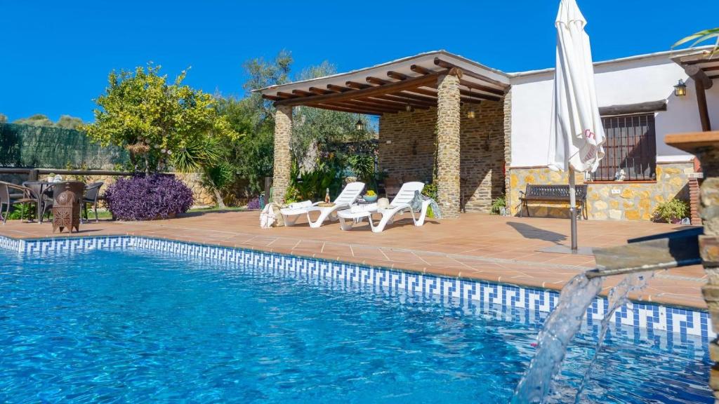 - une piscine avec une terrasse, des chaises et un parasol dans l'établissement Al Hayón Órgiva by Ruralidays, à Órgiva