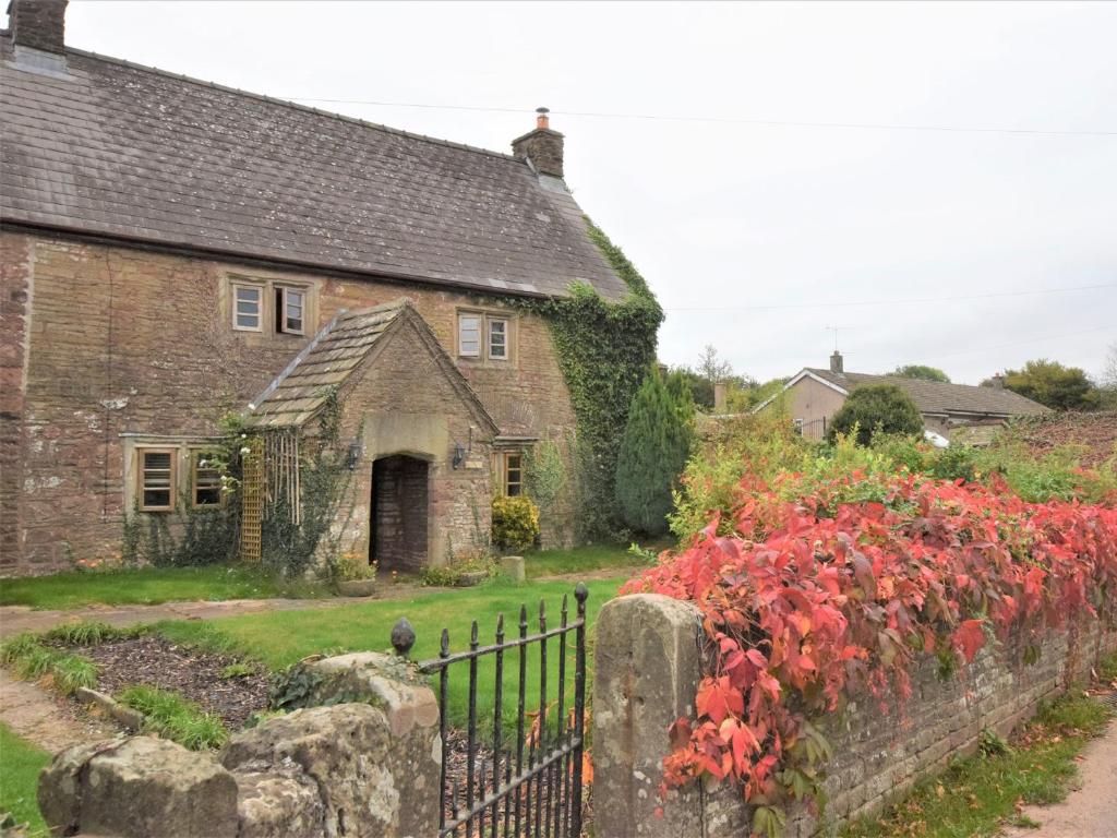 una vieja casa de piedra con una valla y flores en 3 bed in Coleford 52148 en Bream