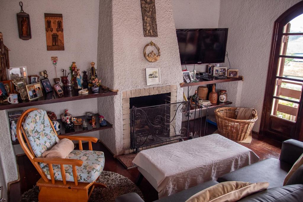 een woonkamer met een open haard en een stoel bij Casa com lareira e Wi Fi em Campos do Jordao SP in Campos do Jordão