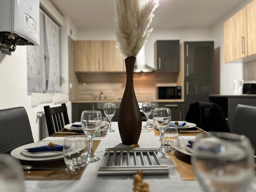 a dining room table with a vase with wine glasses at Home Family Duplex Talange in Talange