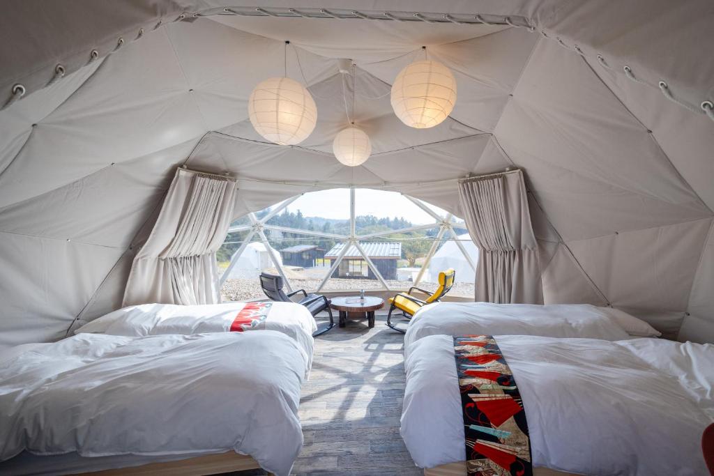 - une chambre avec 2 lits dans une tente dans l'établissement 里山グランピングむすびペット棟, à Mizunami