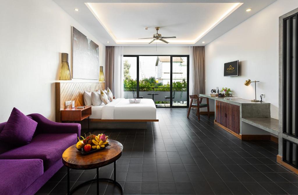 pokój hotelowy z łóżkiem i fioletową kanapą w obiekcie Grand Yard La Residence w Siem Reap