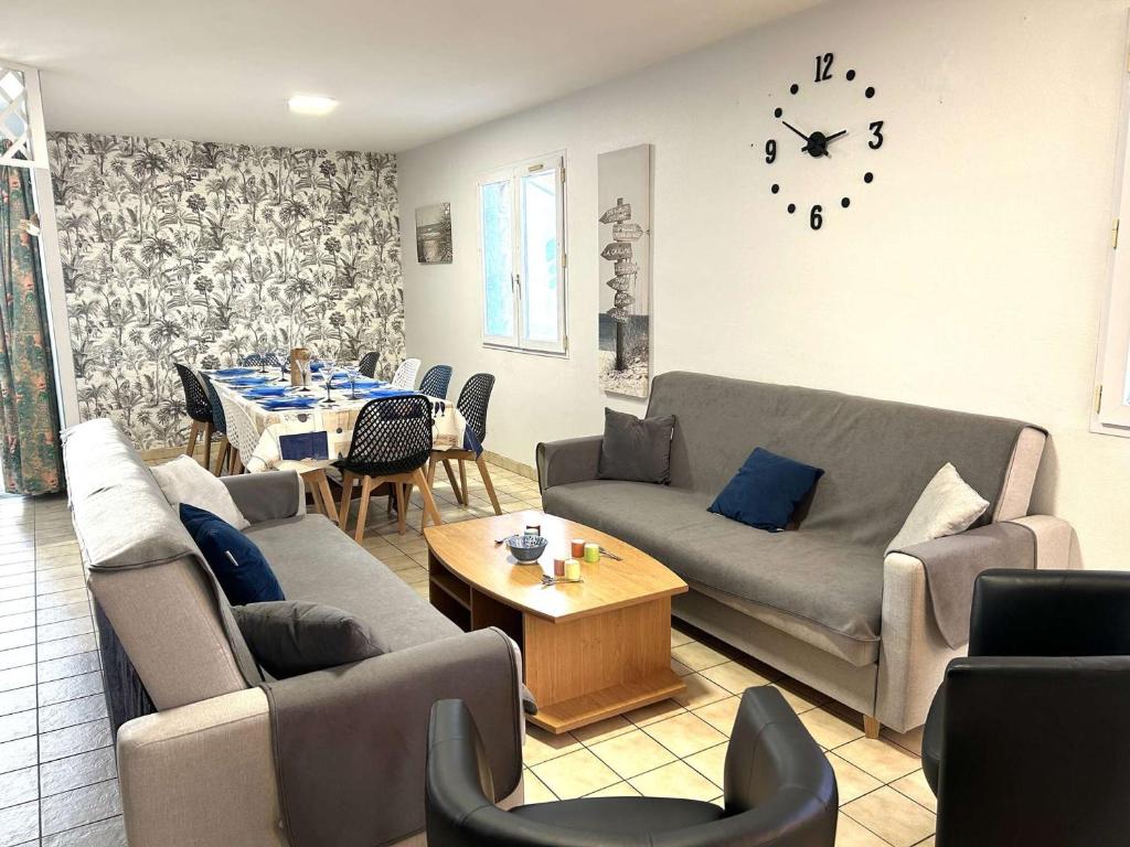 - un salon avec des canapés, une table et une horloge dans l'établissement Maison 4 pièces, 8 couchages, proche plage et centre-ville, avec jardin et garage - FR-1-224-750, à Saint-Gilles-Croix-de-Vie