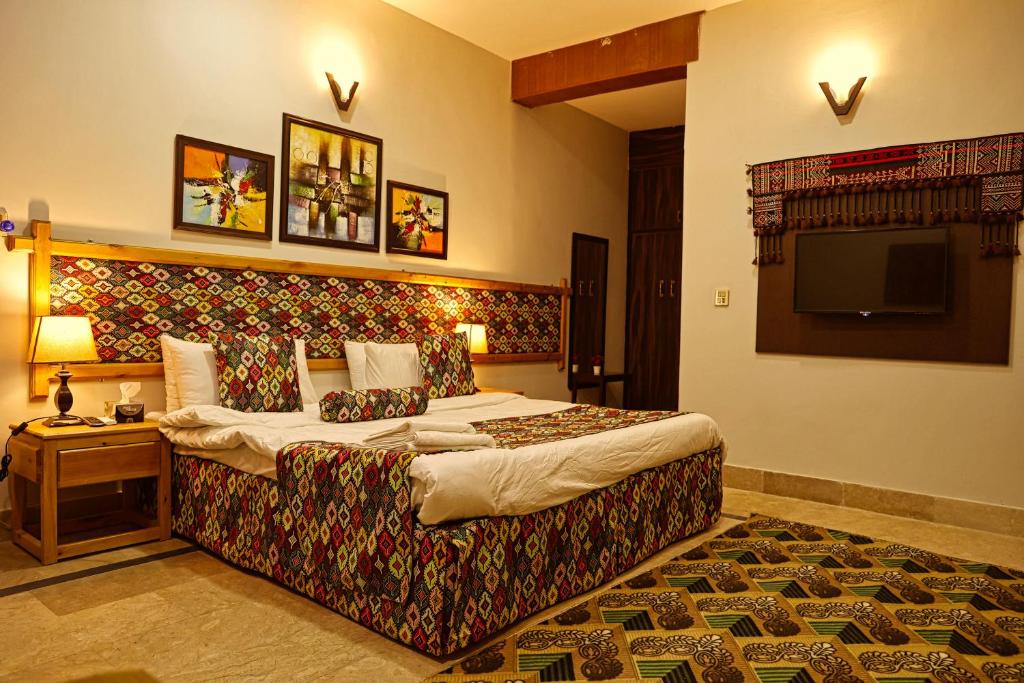 a bedroom with a large bed and a television at Oak Residency in Gilgit