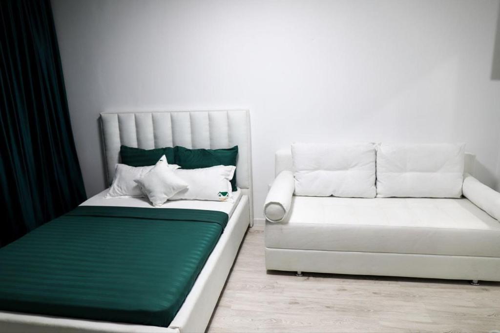 1 cama blanca y 1 sofá en una habitación en Апартаменты в ЖК Каркын, en Kostanái