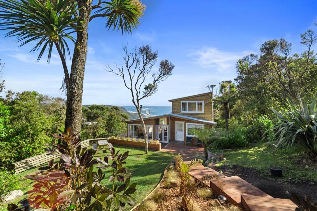 a house with a garden and palm trees at Piha - City Escape, Piha Holiday Home in Piha