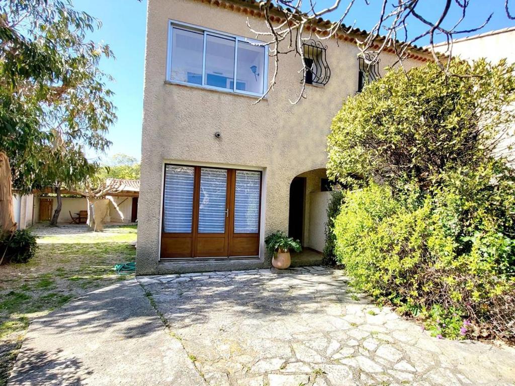 une maison avec une porte marron et une fenêtre dans l'établissement Maison T3 à Six-Fours avec Jardin, Parking Privé, Wi-Fi et Proche Plages - FR-1-316-317, à Six-Fours-les-Plages