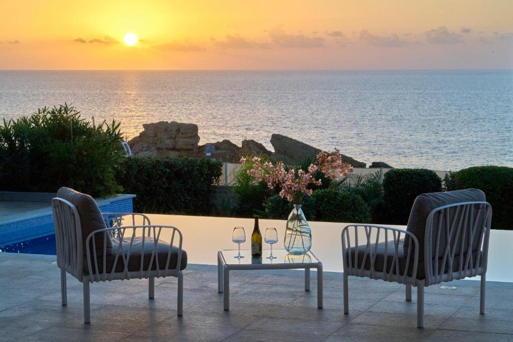 帕福斯的住宿－Olymp Luxury Villa D，一张桌子、两把椅子和一张桌子及酒杯