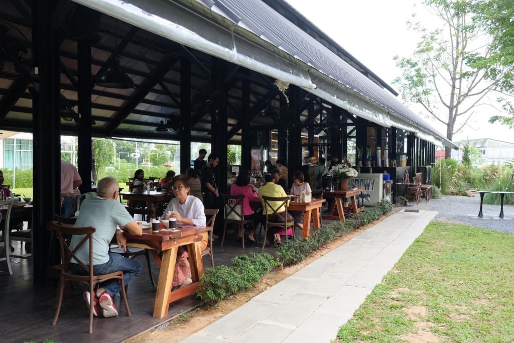 un grupo de personas sentadas en mesas en un restaurante en Punn Hotel Korat en Nakhon Ratchasima