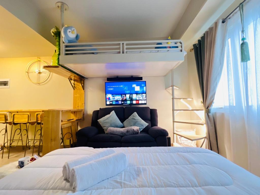 1 dormitorio con cama, sofá y TV en Comfy studio room, en Bacolod