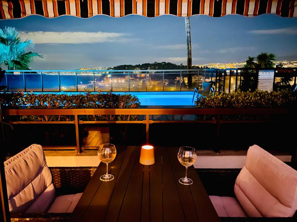 dois copos de vinho sentados numa mesa na varanda em Superbe 2 pièces TERRASSE / PISCINE / VUE / PARKING em Nice