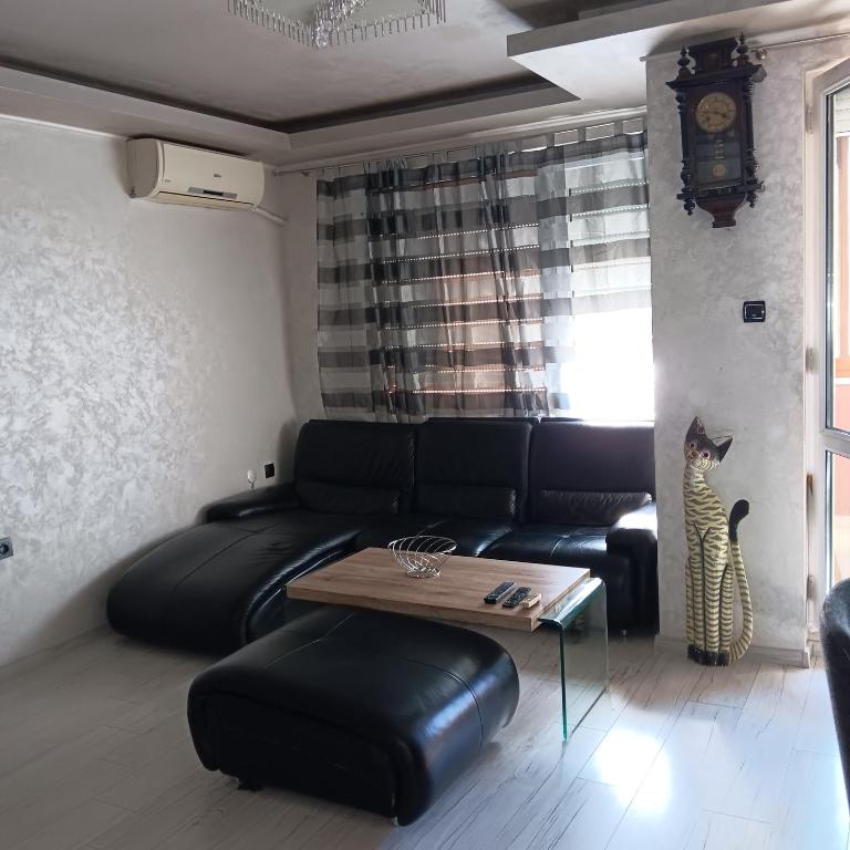 uma sala de estar com um sofá de couro preto e uma mesa em Апартамент МИА em Plovdiv