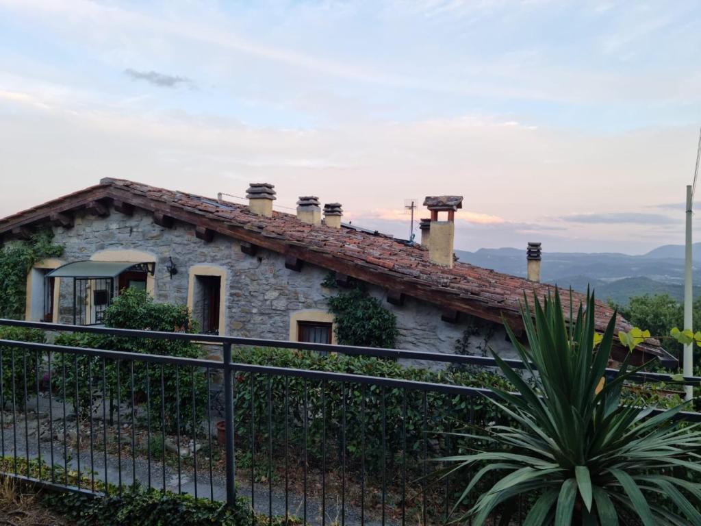 una casa de piedra en una colina con una valla en Casa di sotto, en Giratola