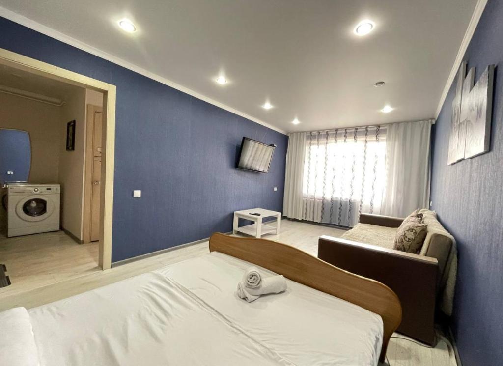 1 dormitorio con 1 cama grande y pared azul en Сокол en Petropavlovsk