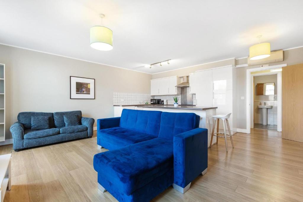 a living room with a blue couch and a kitchen at 221 Clapham Road Apartments in London