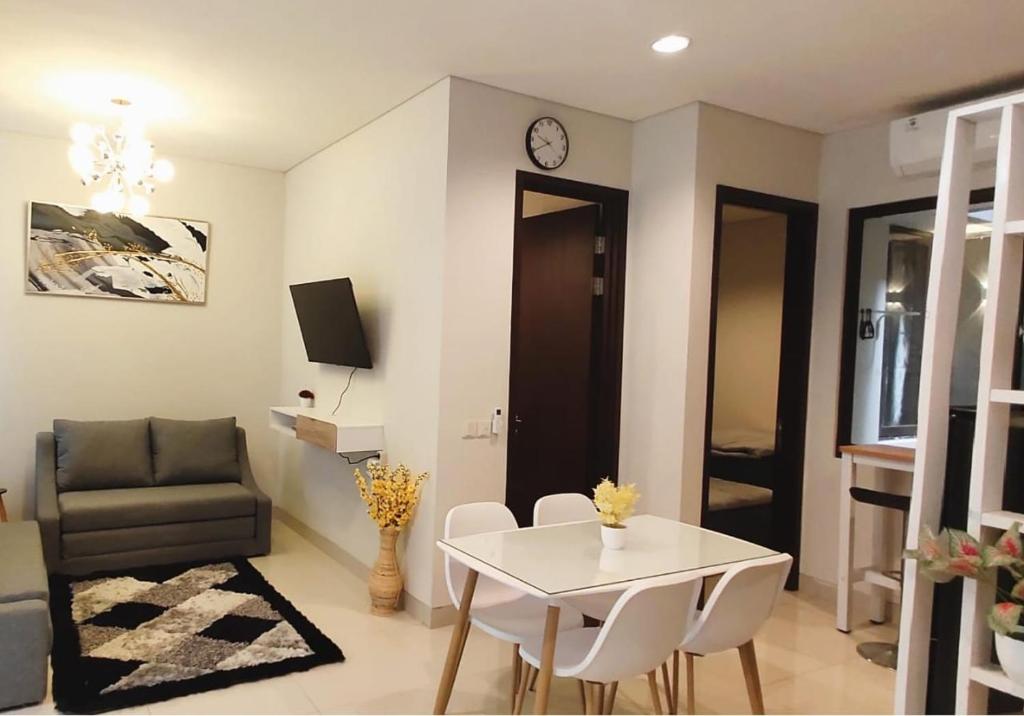 a living room with a table and a couch and a clock at Regentown Home near ICE BSD in Tjilandak