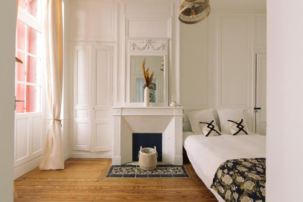 - une chambre blanche avec une cheminée et un lit dans l'établissement By Homy, à Bordeaux