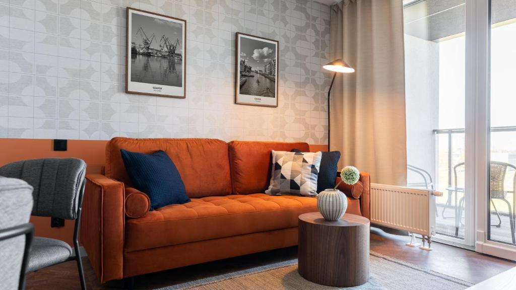 an orange couch sitting in a living room at Flatbook - City Center Apartments Chlebova with Gym in Gdańsk