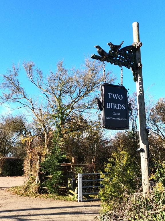 a two birds sign hanging from a pole at Two Birds Weekly Stay in Malmesbury