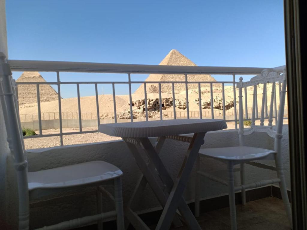 开罗Yamour Pyramids View的阳台享有金字塔美景,配有一张桌子和两把椅子。