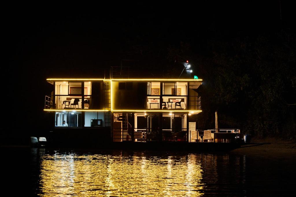 uma casa num barco na água à noite em El Manatí - River Experience em Iquitos