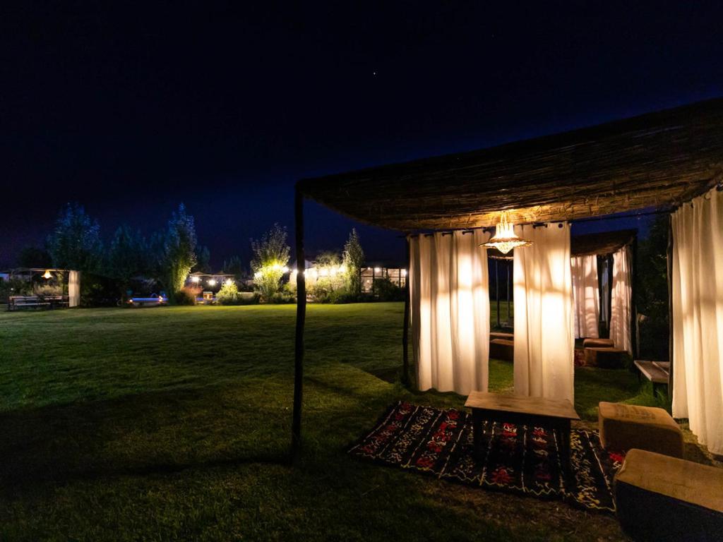 a gazebo with lights in a field at night at Chalet au Calme à la Ferme in Fez