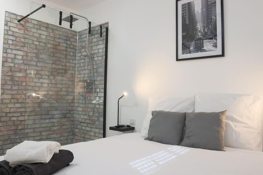 - une chambre avec un lit blanc et un mur en briques dans l'établissement {Le Factory}, proche EuroAirport, à Saint-Louis